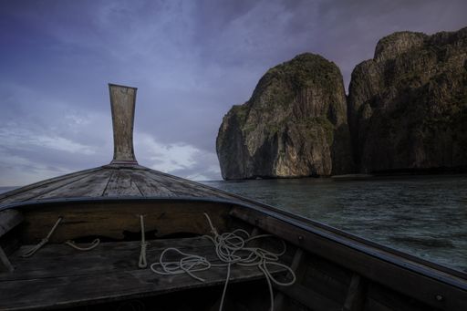 A beautiful shot of a wooden boat isolated on a calm sea near the cliffs under the breathtaking sky
