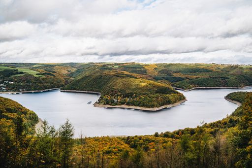 A high angle shot of a beautiful lake surrounded by hills in autumn under the cloudy sky