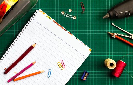 A top view of a green gridded desk with various stationery