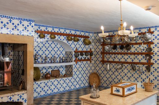 A beautiful shor of an antique kitchen with tile walls with  patterns and old tableware hanged on the walls