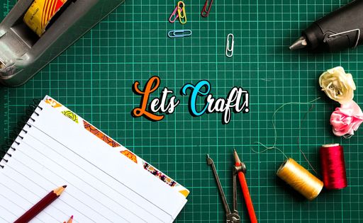 A top view of a green gridded desk with an inscription 'lets craft' between various stationery