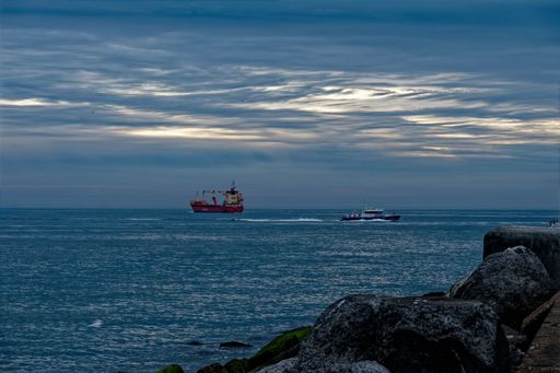 A few ships sailing in the open sea against the background of the blue sky at dusk