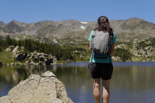 A young female looking at the lake view while hiking in the Lac des Bulloses mountains in France