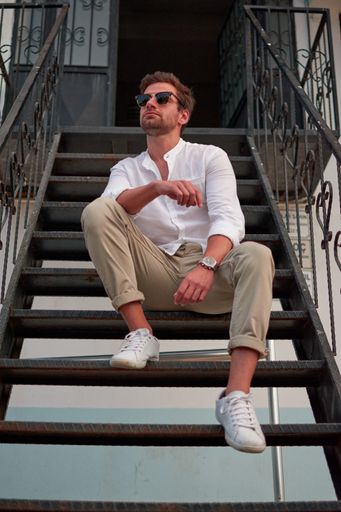 A vertical shot of a male with sunglasses sitting on the stairs