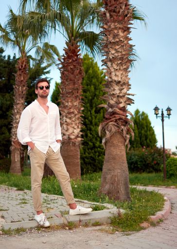 A vertical shot of a male standing confidently in a park