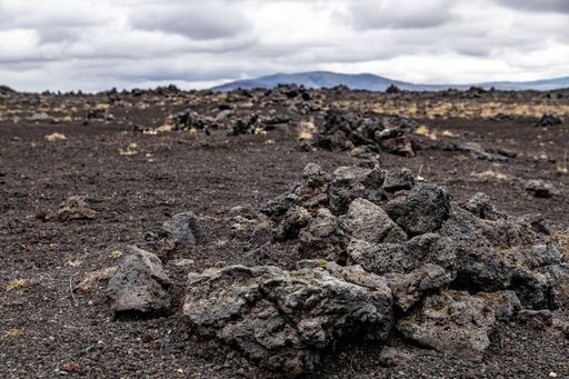 A rocky wasteland in Iceland with silhouettes of distant mountains in the background under a cloudy sky