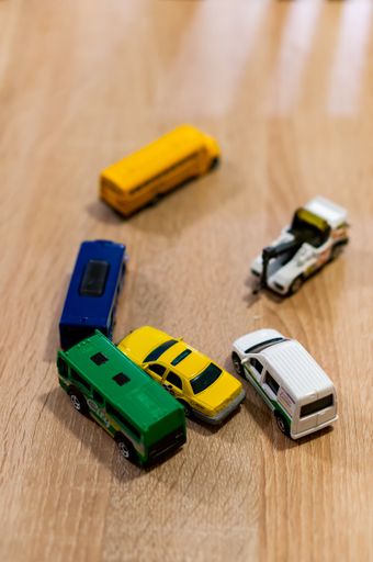 Mix of toy cars laying on a wooden floor including Matchbox and Siku brand. Vertical high angle view