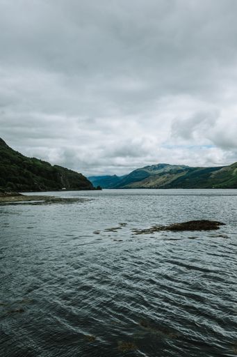 A vertical shot of a beautiful lake surrounded by hills on a gloomy day