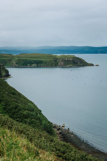 A vertical shot of a big cliff and a big lake on a gloomy day on Skye island