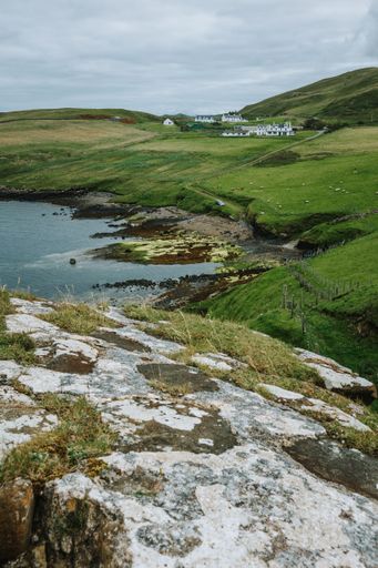 A vertical shot of a lake surrounded by green landscape during a cloudy day