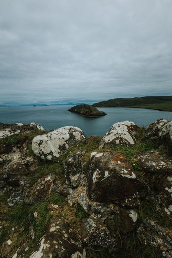 A vertical shot of a lake surrounded by green landscape during a cloudy day