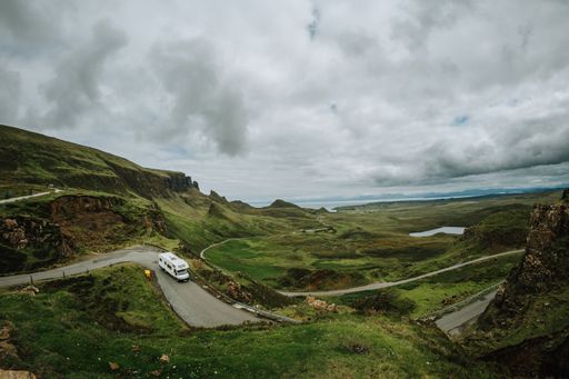A car driving along a trail on Skie island in Scotland captured under a grey cloudy sky