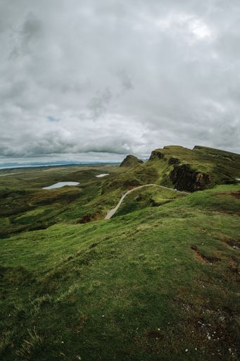 A vertical of hills and a trail on Isle of Skie island in Scotland captured under a grey cloudy sky