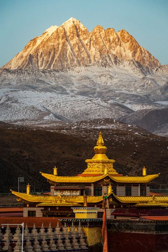 A scenic shot of the Tagong temple and Yala mountain covered in snow in Sichuan, China