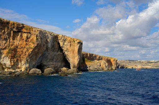 A landscape shot of the Fungus Rock on the coast of Gozo under the cloudy blue sky in Malta