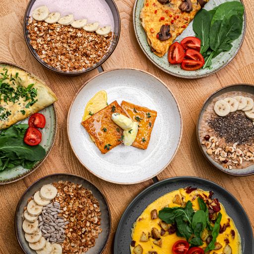 A closeup of breakfast dishes on plates containing fruits and vegetables