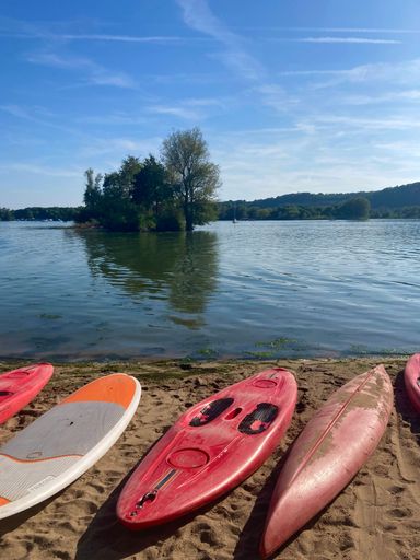 A vertical shot of Maas river shore in Limburg, the Netherlands with stand up paddles, canoes and kayaks on a sunny day