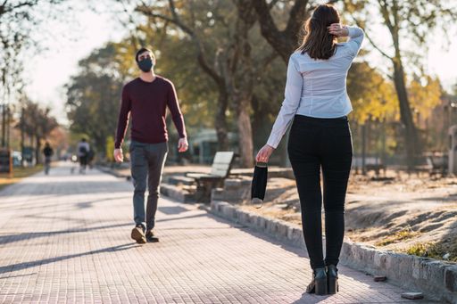 A shot of a couple keeping distance, a female without a mask - the new normal concept