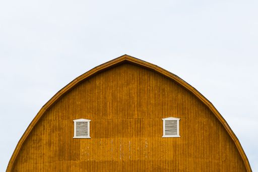 A yellow barn top with two windows under the cloudy sky in Toten, Norway