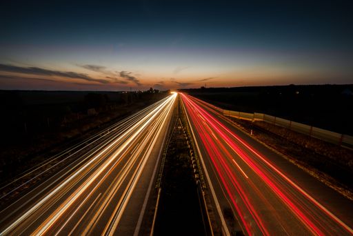A long exposure shot of red and yellow car lights on a highway in the evening