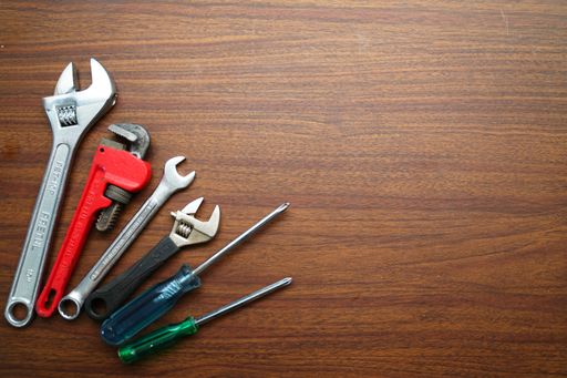 Different types of adjustable wrenches and other tools on a wooden table