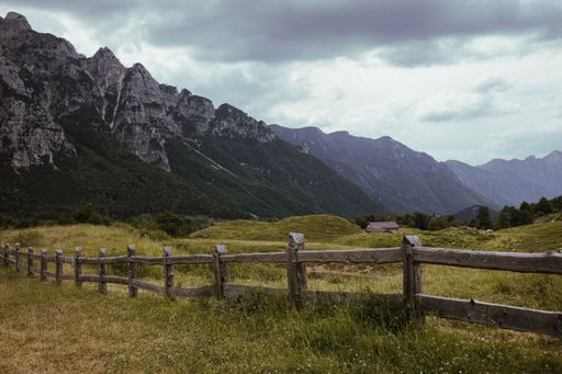 A scenic shot of a field with wooden fence surrounded by hills in North Italy