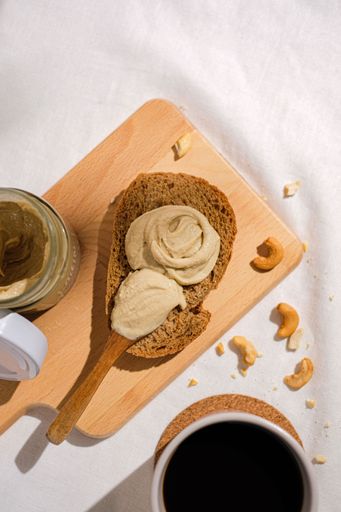 The vertical top view of the almond butter on a slice of bread on the cutting board