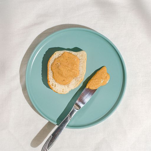 The top view of the bread and knife covered in peanut butter in the blue plate