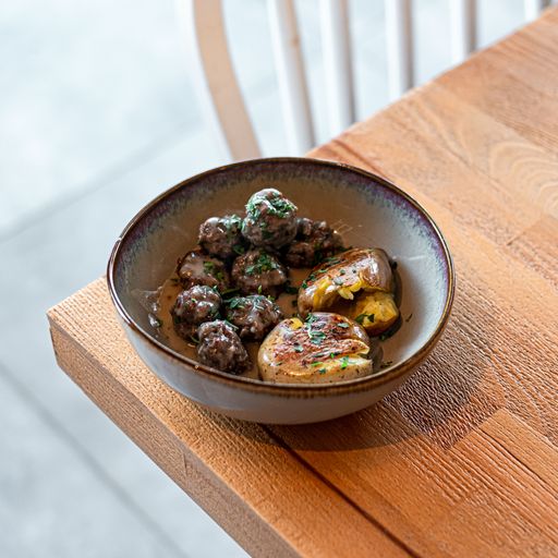 The high-angle view of meatballs and potatoes in the bowl on a wooden table