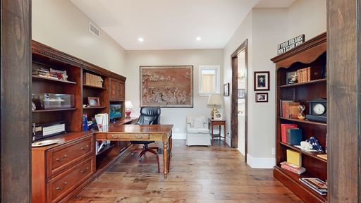 An interior design of office room with office, leather chair, wooden floor and shelves with books