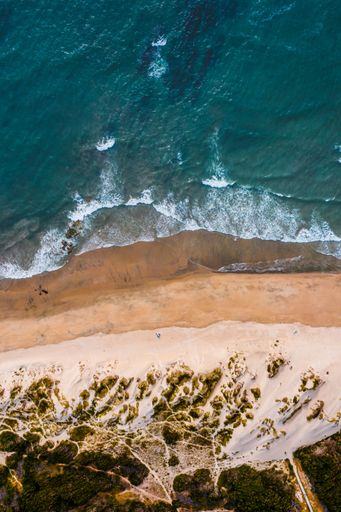 A vertical bird-eye shot of a beach with a blue sea