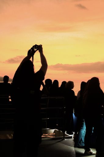 A vertical shot of a human silhouette taking a picture of the sunset with a camera
