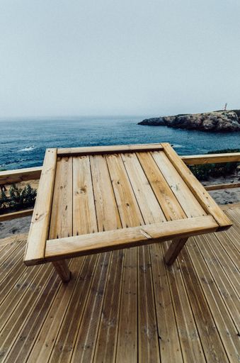 A vertical shot of a wooden table in the cafe on the shore in Porto Covo, Alentejo, Portugal