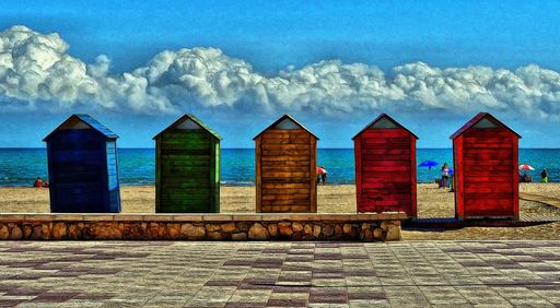 A beautiful shot of five colorful huts in a public beach with the breathtaking sky in the background