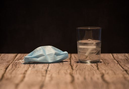 A closeup shot of a medical face mask and a glass of water