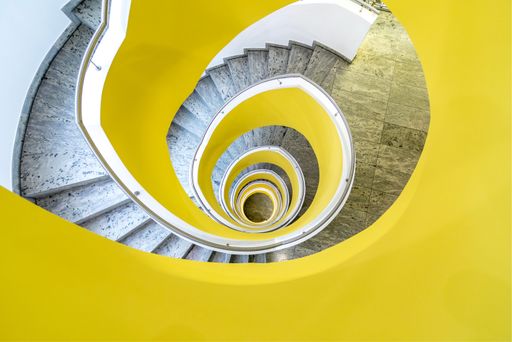 A top view of spiral staircase with yellow metal railings