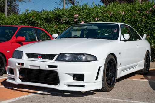 A white Nissan Skyline GT-R R33 parked on the street