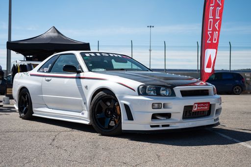 A White Nissan Skyline GT-R R34 parked on the street