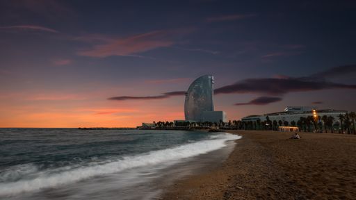 A beautiful shot of a beach under the evening sky with a modern building in the background