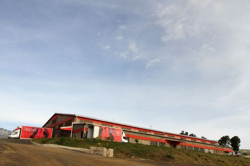A low angle shot of a large warehouse with semi-trailer trucks parked outside