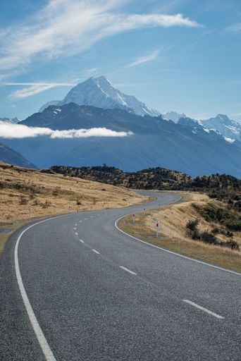 A vertical shot of the Mount Cook road in New Zealand with snowy mountains in the background