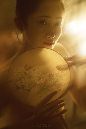 A vertical shot of a beautiful Asian girl doing needlework of flowers with blurred background