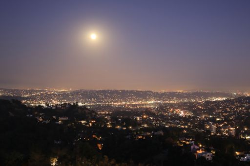 An aerial shot of a beautiful cityscape with a lot of illuminated buildings at night time