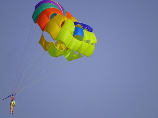 A mesmerizing shot of a couple flying with a parachute high in the sky
