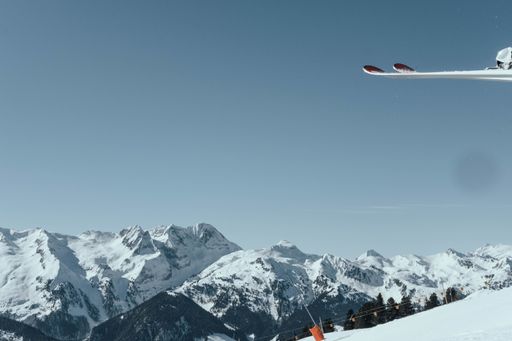 A beautiful shot of an airplane flying over high rocky mountains covered with snow