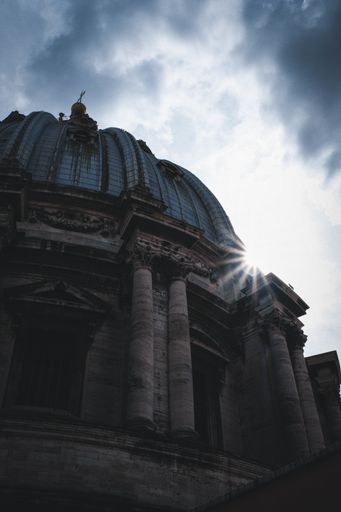 A vertical low angle shot of a temple with a round dome under the beautiful cloudy sky