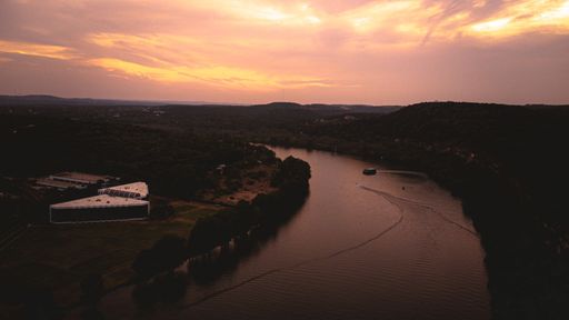 An aerial view of Austin river surrounded by growing trees during sunset