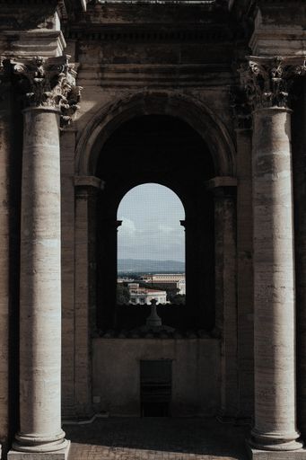 A vertical shot of the inside of a temple with an arch window and the beautiful cityscape in the background