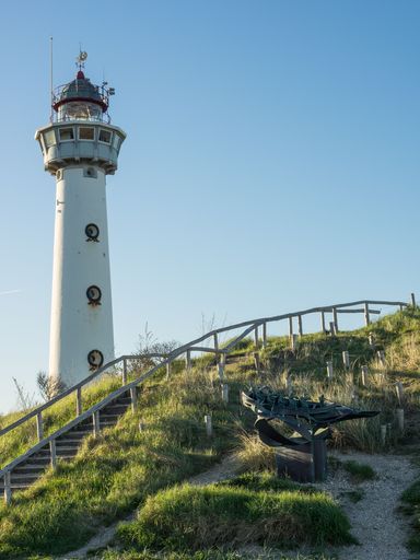 A vertical shot of a lighthouse on a green hill near stairs in Egmond aan Zee, Netherlands