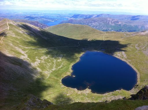 A drone shot of a small lake surrounded by mountains